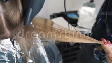 染色时吹毛。 用<strong>吹风</strong>机和圆毛刷烘干棕色长发。 特写镜头。